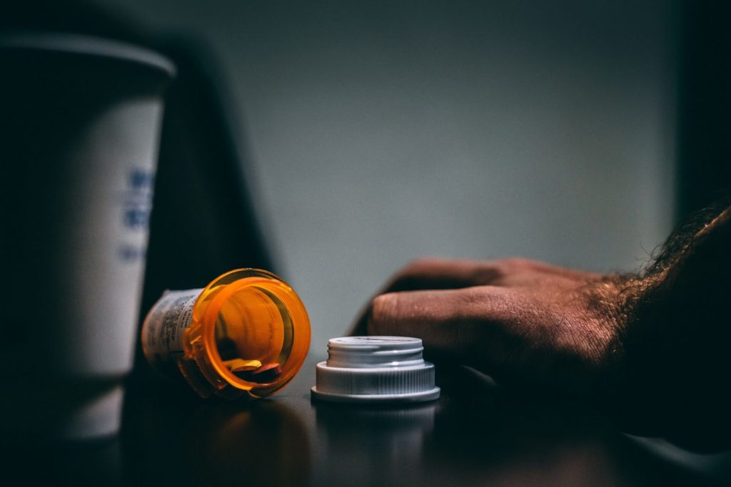 Overturned pill bottle on counter by a man's hand