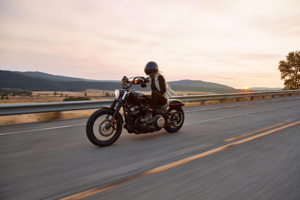 Female motorcyclist riding on paved road at sunset