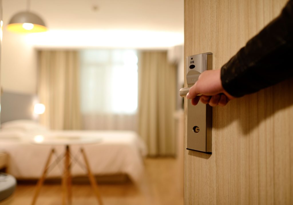 Hotel room being opened by a suited hotel staff hand.