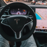 A drivers point of view of a tesla steering wheel and dash.